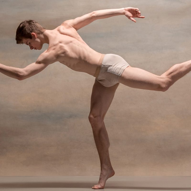 the-male-ballet-dancer-posing-over-gray-P9JN9XF.jpg